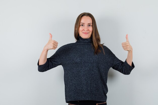 Young lady showing double thumbs up in shirt and looking confident