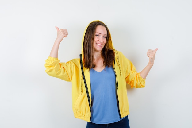 Young lady showing double thumbs up in t-shirt, jacket and looking confident