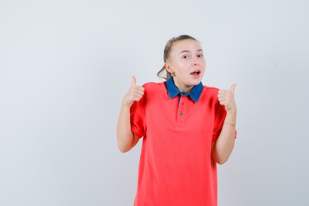Young lady showing double thumbs up in t-shirt and looking merry