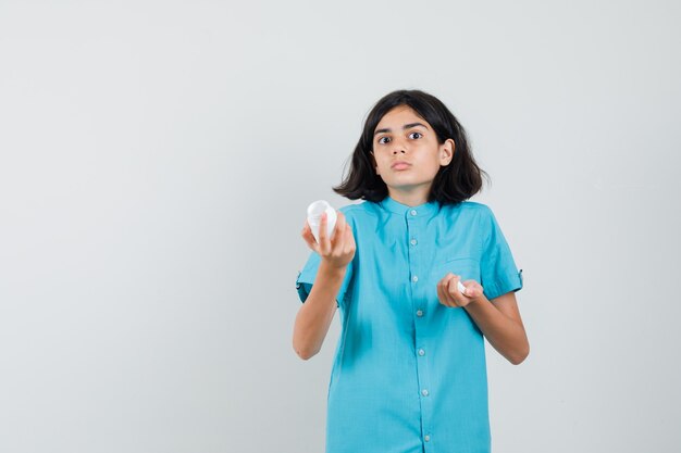 Young lady showing empty bottle of pills in blue shirt and looking helpless.