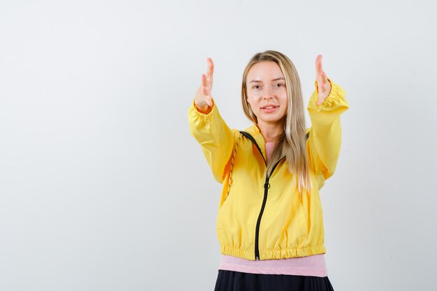 Young lady showing giving gesture in t-shirt, jacket and looking confident