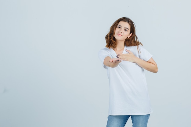 Tシャツ、ジーンズ、キュートに見える、正面図でジェスチャーを与える若い女性。