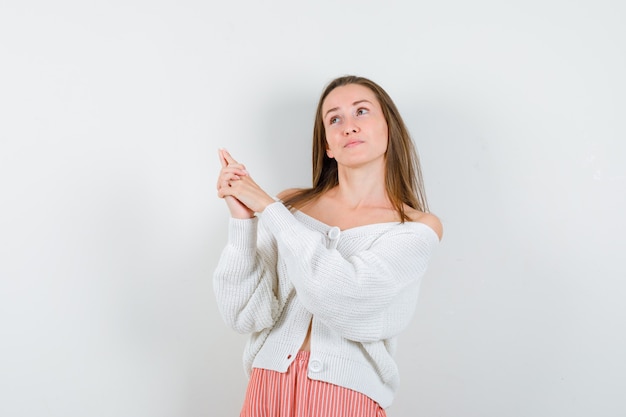 Young lady showing gun gesture in cardigan and skirt looking confident isolated