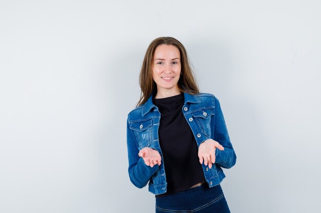 Young lady showing helpless gesture in blouse, jacket and looking confident , front view.