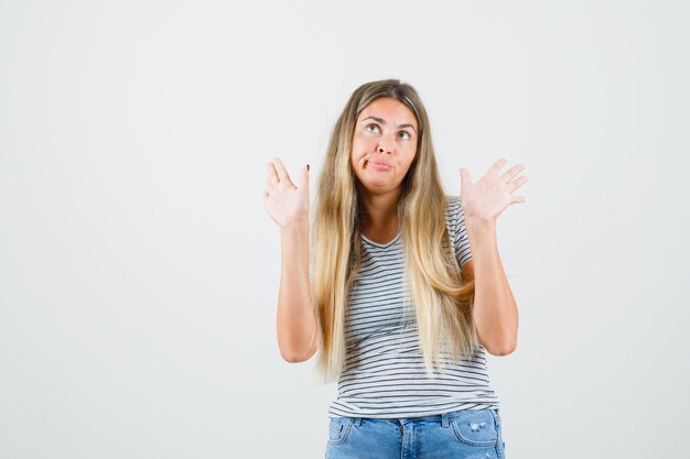 Young lady showing i dont know gesture in t-shirt and looking lazy , front view.