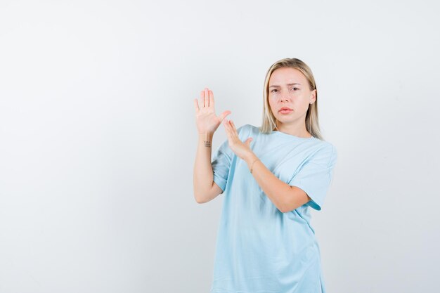 Young lady showing karate chops gesture in t-shirt isolated