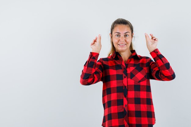 Young lady showing meditation gesture in checked shirt and looking cheerful