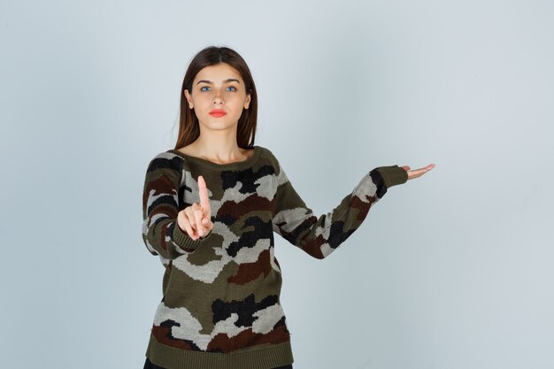 Young lady showing a minute gesture while pretending to show something in sweater