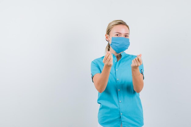 Young lady showing money gesture in t-shirt, mask and looking careful