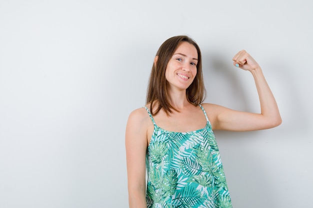 Young lady showing muscles of arm and looking merry. front view.