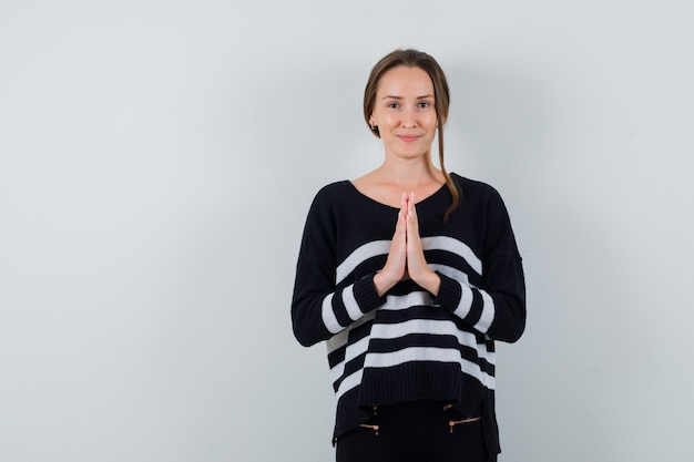 Foto gratuita giovane signora che mostra il gesto di namaste in camicia e che sembra carino