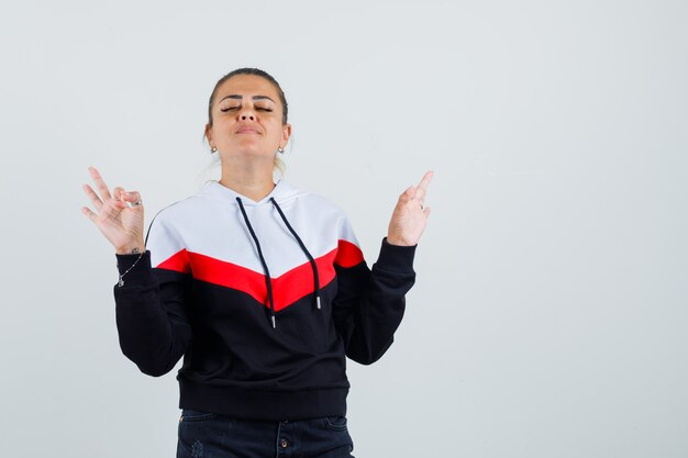 Young lady showing ok gesture in colorful sweatshirt and looking relaxed , front view.