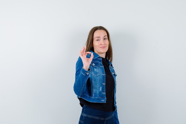 Young lady showing ok gesture in shirt, jacket and looking confident. front view.