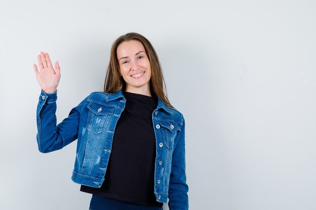 Young lady showing palm in blouse, jacket and looking confident , front view.