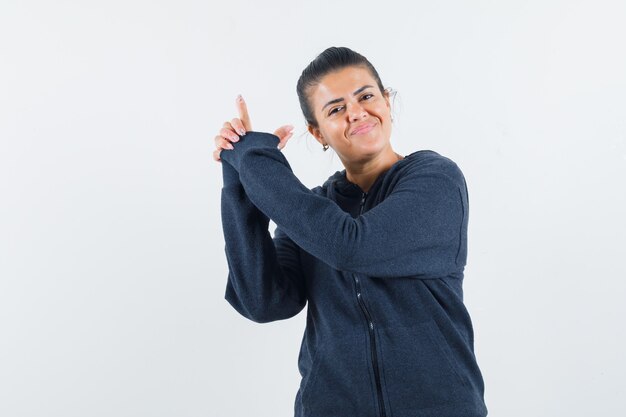 Young lady showing pistol gesture in jacket and looking satisfied 