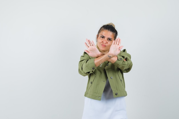 Young lady showing refusal gesture in t-shirt jacket and looking annoyed 