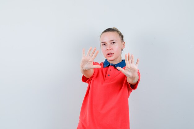 Young lady showing refusal gesture in t-shirt and looking serious