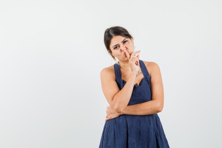 मुफ़्त फोटो young lady showing silence gesture in dress and looking careful