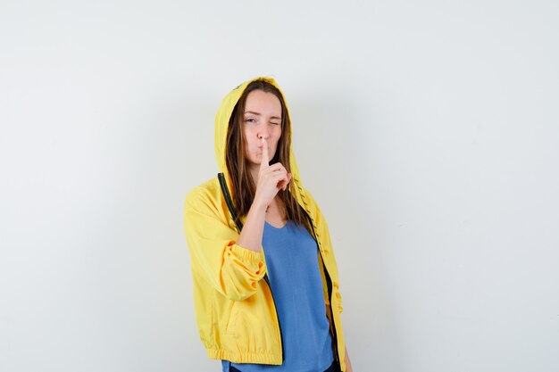 Young lady showing silence gesture in t-shirt, jacket and looking confident , front view.