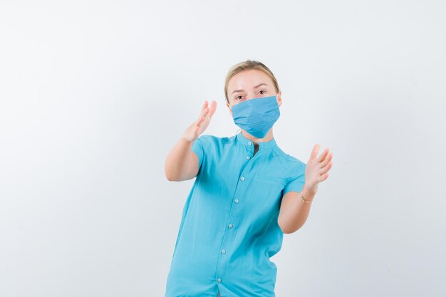 Young lady showing size sign in t-shirt, mask and looking confident