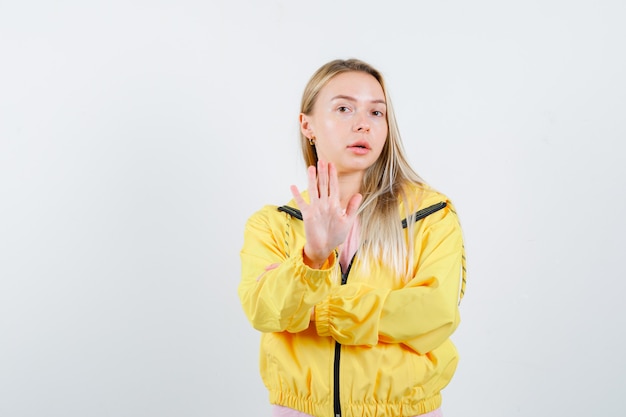Бесплатное фото Молодая леди показывает жест стоп в футболке, куртке и выглядит уверенно