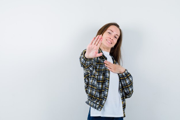 Young lady showing stop gesture in t-shirt, jacket and looking confident. front view.