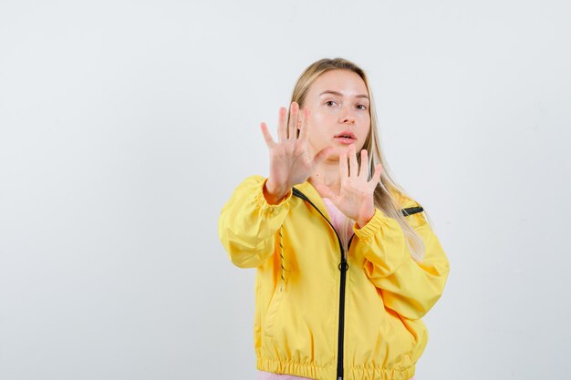 Young lady showing stop gesture in t-shirt, jacket and looking confident