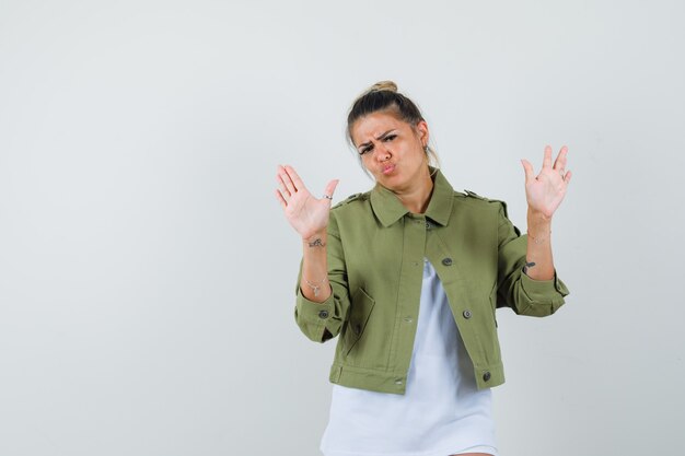 Young lady showing stop gesture in t-shirt jacket and looking irritated 