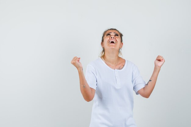 Young lady showing winner gesture in t-shirt and looking happy