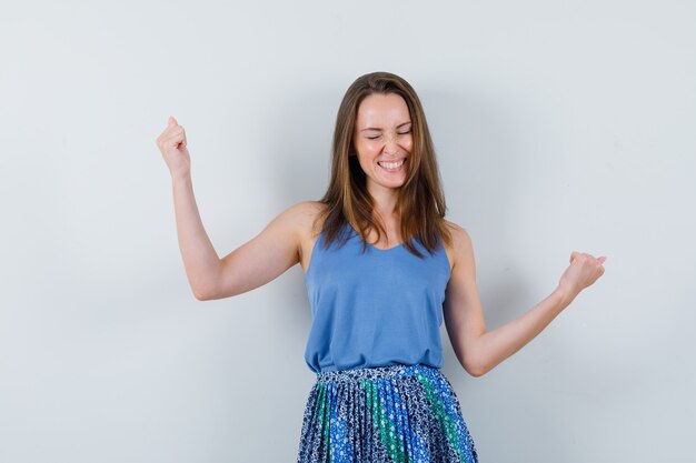 Young lady in singlet, skirt showing winner gesture and looking lucky