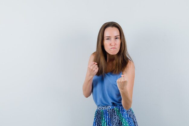 Young lady in singlet, skirt standing in fight pose and looking spiteful