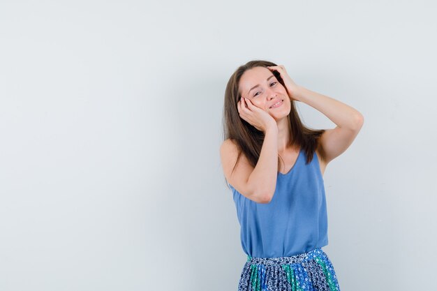 Giovane donna in canottiera, gonna che tocca la pelle del viso e sembra carina