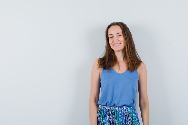 Young lady in singlet, skirt winking eye and looking cheerful