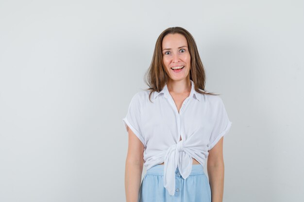 Young lady smiling in blouse and skirt and looking joyous