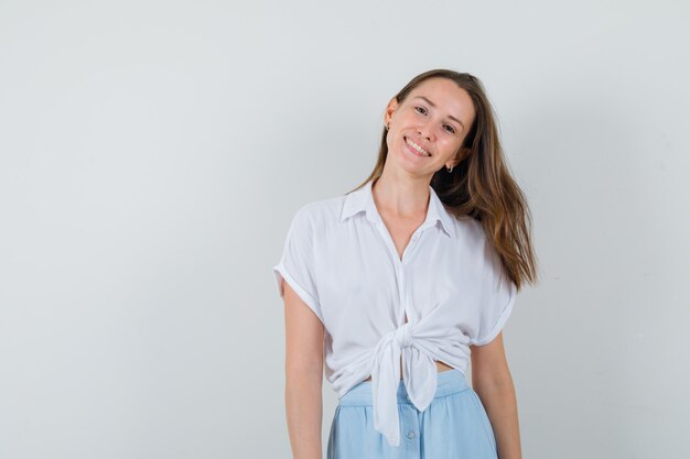 Young lady smiling while looking at front in blouse, skirt and looking positive