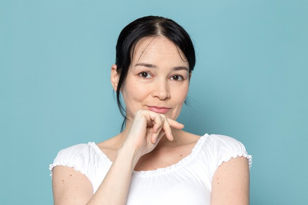 young lady smiling with her hand on jaw on blue