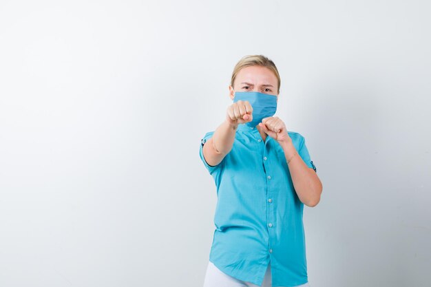 Young lady standing in fight pose in t-shirt, mask and looking serious