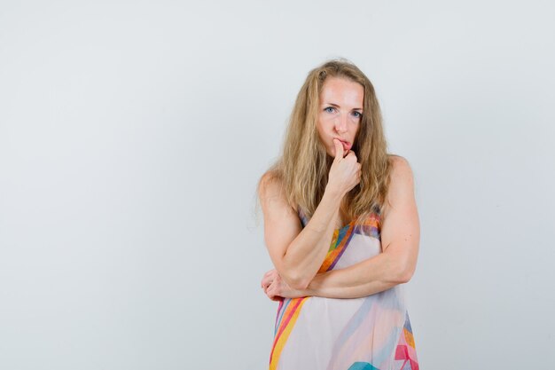 Young lady standing in thinking pose in summer dress and looking helpless 