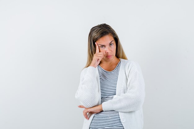 Young lady standing in thinking pose in t-shirt, jacket and looking sad , front view.