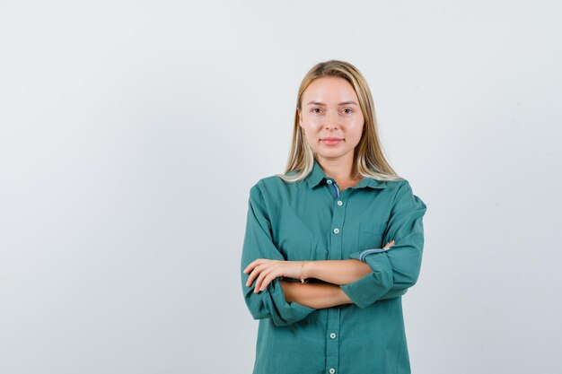 Young lady standing with crossed arms in green shirt and looking confident.