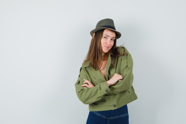 Free photo young lady standing with crossed arms in jacket pants hat and looking elegant