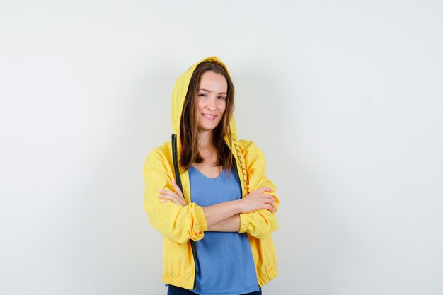 Young lady standing with crossed arms in t-shirt, jacket and looking charming , front view.