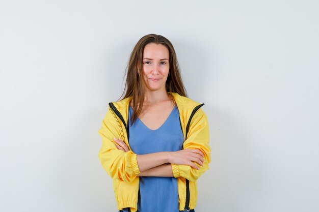 Young lady standing with crossed arms in t-shirt, jacket and looking confident , front view.