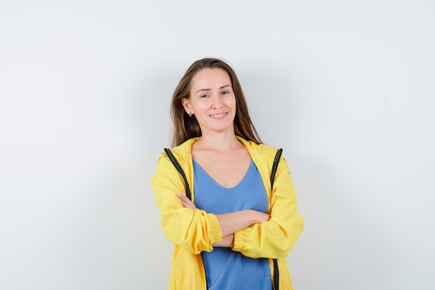 Free photo young lady standing with crossed arms in t-shirt and looking confident , front view.