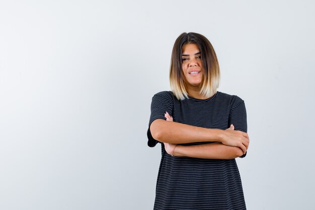 Young lady standing with crossed arms while looking at camera in polo dress and looking confident. front view.