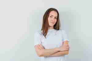 Free photo young lady standing with crossed arms in white t-shirt and looking confident