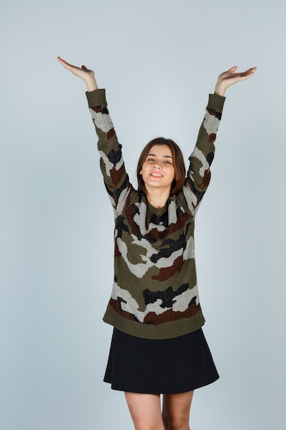 Young lady stretching upper body in sweater, skirt and looking merry