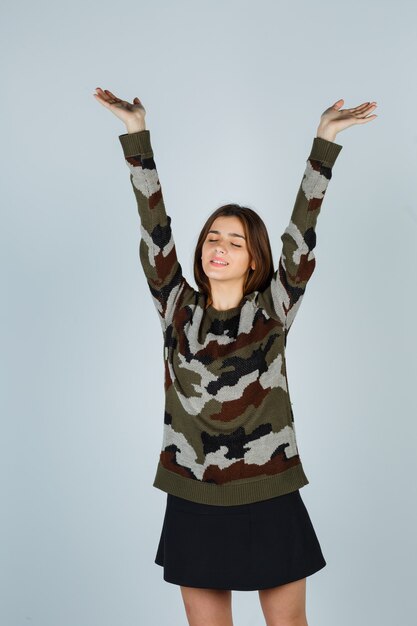 Young lady stretching upper body in sweater, skirt and looking sleepy