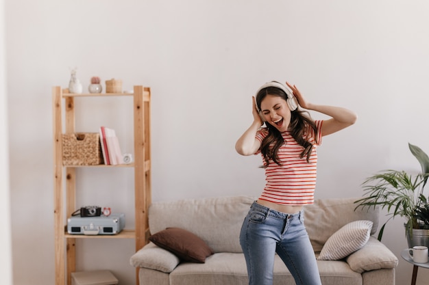 Free photo young lady in striped red t-shirt and blue jeans is resting and dancing