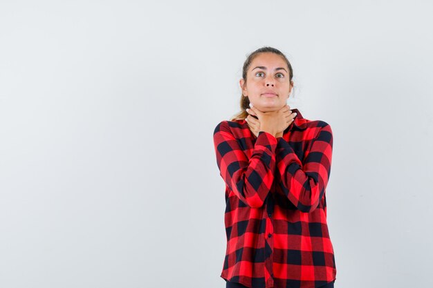Young lady suffering from sore throat in checked shirt and looking sick